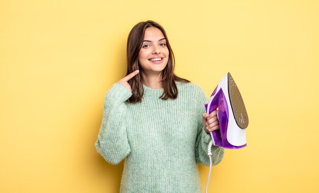 Mooie vrouw glimlachend vol vertrouwen wijzend naar eigen brede glimlach. ijzeren kleding concept