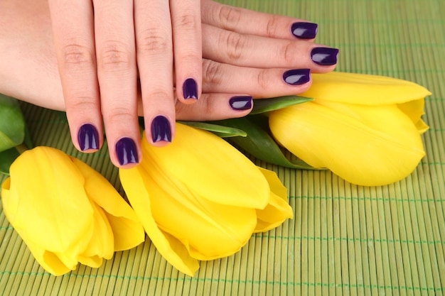 Mooie vrouw handen met bloemen op bamboe achtergrond