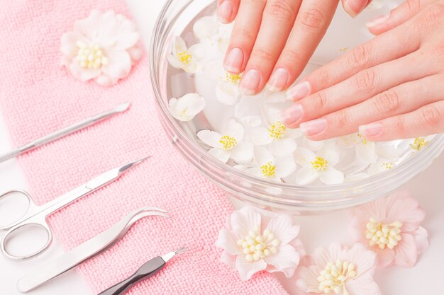 Mooie vrouw handen met manicure in kom met water