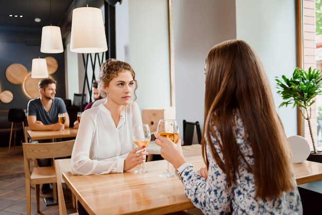 Mooie vrouw het drinken wijn met vrouwelijke vriend in restaurant.