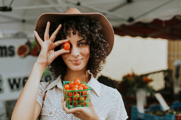 Mooie vrouw het kopen tomaten bij een landbouwersmarkt