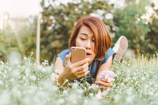 mooie vrouw holding en slimme telefoon gebruiken in de tuin.