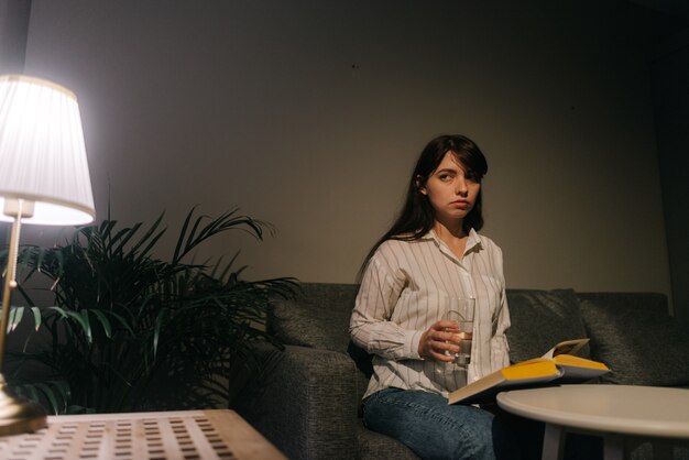 Mooie vrouw houdt een glas water in de hand in een donkere kamer