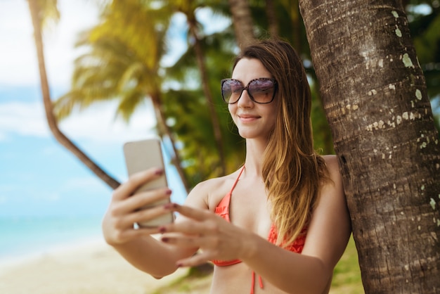 Mooie vrouw in bikini die selfie op mooie tropisch nemen