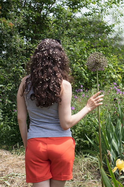 Mooie vrouw in de buurt van planten in de zomertuin.