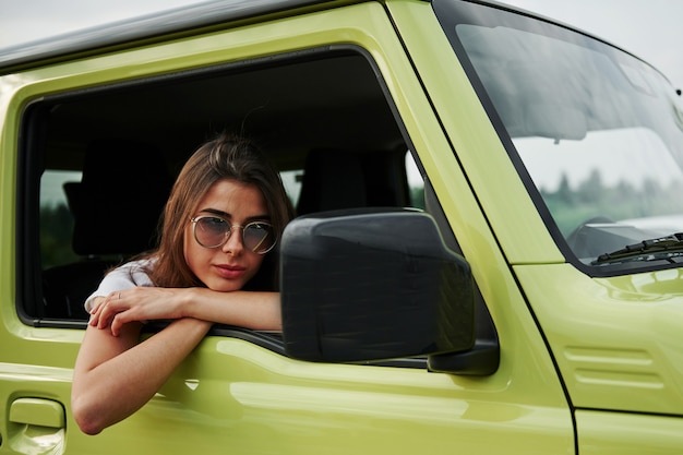 Mooie vrouw in de groene moderne auto poseren voor de camera.