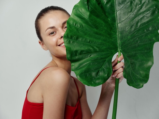 Mooie vrouw in een badpak groen blad in handen close-up