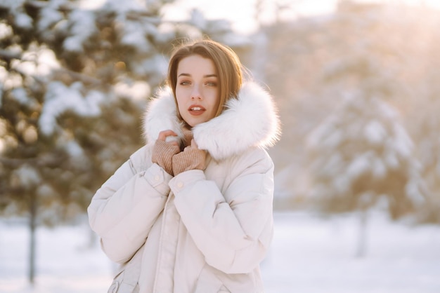 Mooie vrouw in een besneeuwd park Jonge dame die op een zonnige winterdag loopt