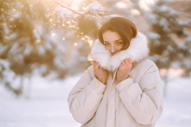 Mooie vrouw in een besneeuwd park Jonge dame die op een zonnige winterdag loopt