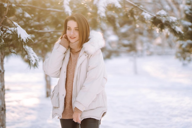 Mooie vrouw in een besneeuwd park. Jonge dame wandelen in een zonnige winterdag.