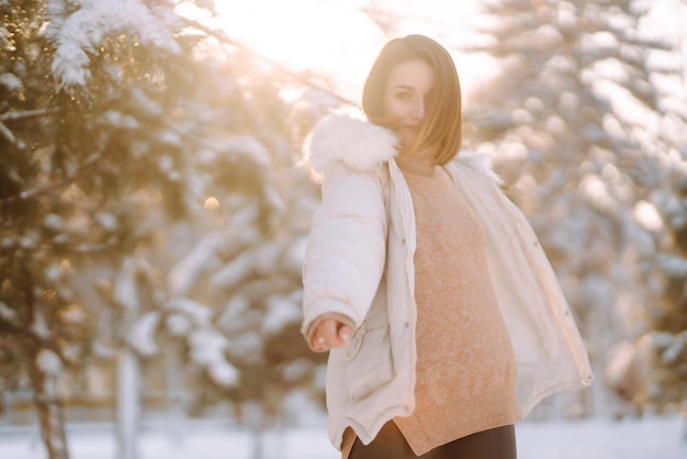 Mooie vrouw in een besneeuwd park. jonge dame wandelen in een zonnige winterdag.