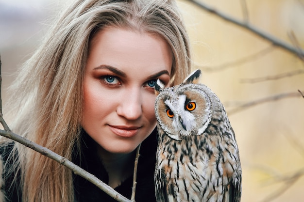 Mooie vrouw in een bontjas met een uil op hand