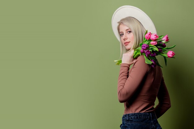 Mooie vrouw in een hoed met tulpenboeket