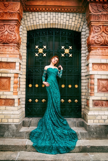Mooie vrouw in een lange groene jurk op oude architectuur