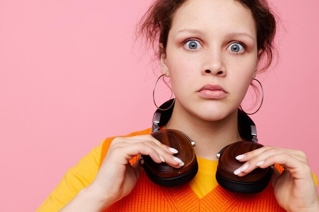 Foto mooie vrouw in een oranje trui koptelefoon muziek entertainment roze achtergrond ongewijzigd