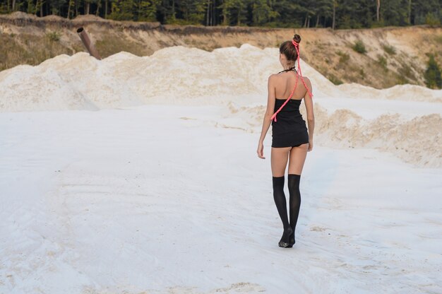 Mooie vrouw in een verleidelijke korte zwarte rok en kousen op het strand