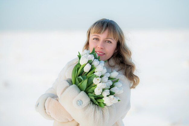 Mooie vrouw in een winterlandschap met een boeket witte tulpen