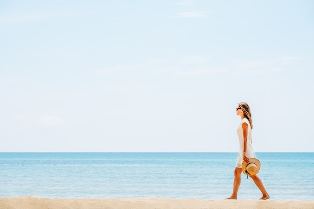 Mooie vrouw in een witte jurk lopen op het strand