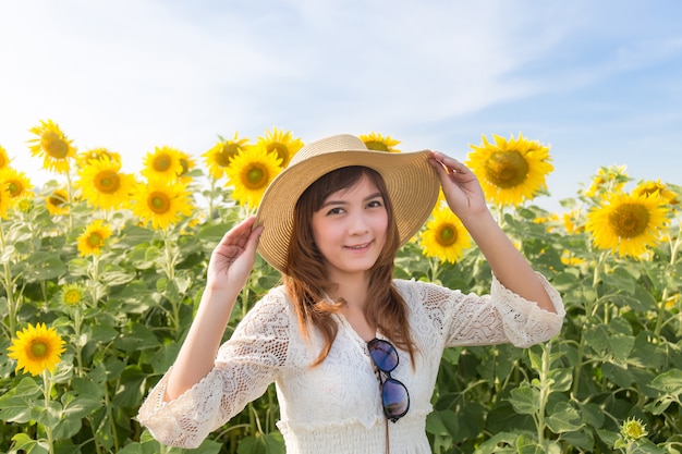 mooie vrouw in een witte jurk op een veld met zomer zonnebloemen