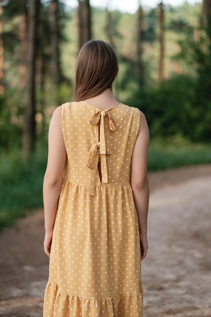 Mooie vrouw in gele zomerjurk buitenshuis