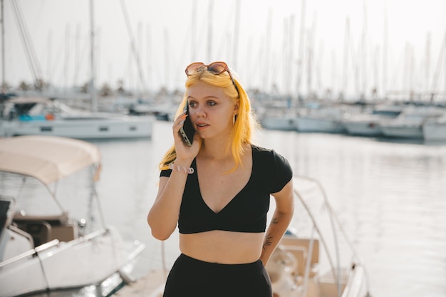 Mooie vrouw in gesprek aan de telefoon tegen de achtergrond van de blauwe zee en jachten