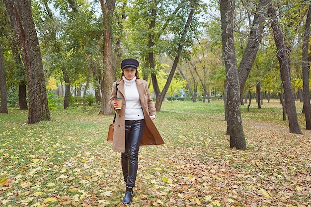 Mooie vrouw in herfstpark met koffie