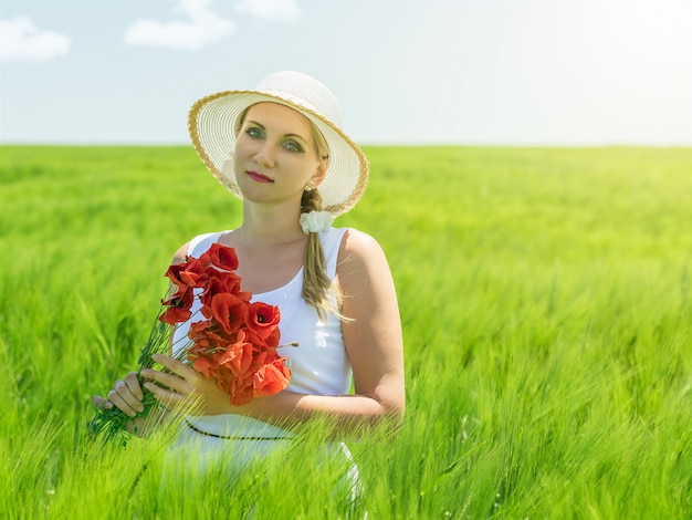 Mooie vrouw in hoed in de zon op een veld van rogge.