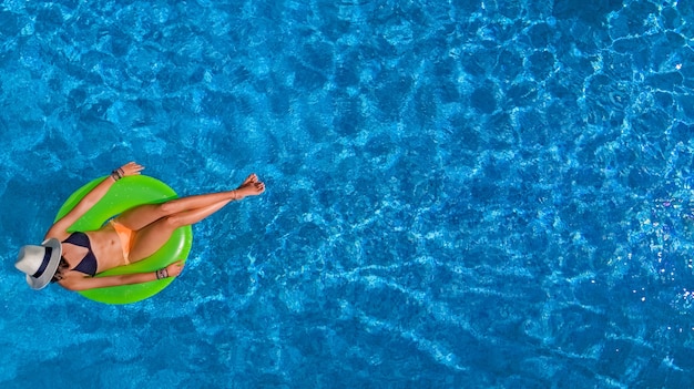 Mooie vrouw in hoed in zwembad luchtfoto van bovenaf, jong meisje in bikini ontspant en zwemt op opblaasbare ring donut en heeft plezier in water op vakantie