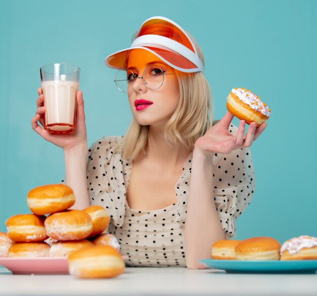 Mooie vrouw in jaren 90 kleding met donuts en melk