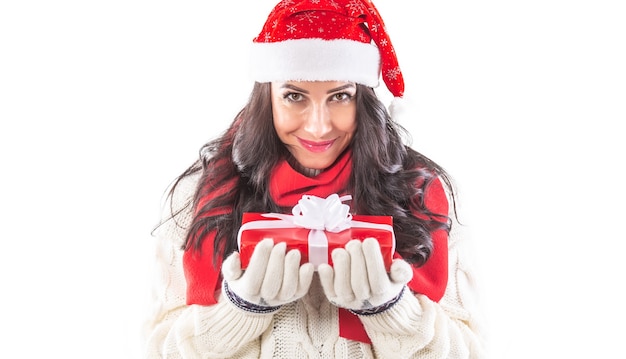 Mooie vrouw in kerstmuts houdt aanwezig met beide handen in handschoenen, glimlachend.