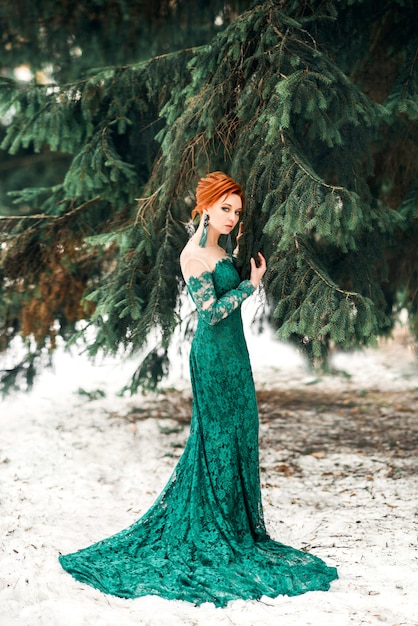 Mooie vrouw in lange groene jurk in de winter op sneeuw