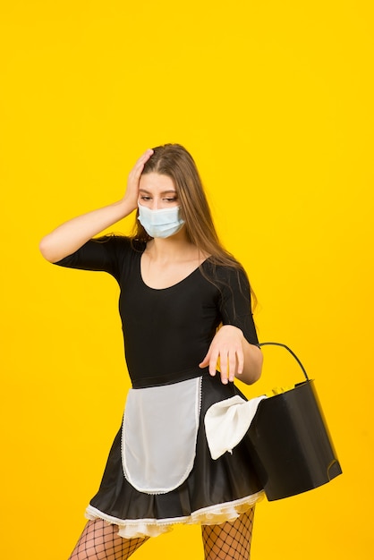 Mooie vrouw in meid kleren poseren in covid beschermend masker