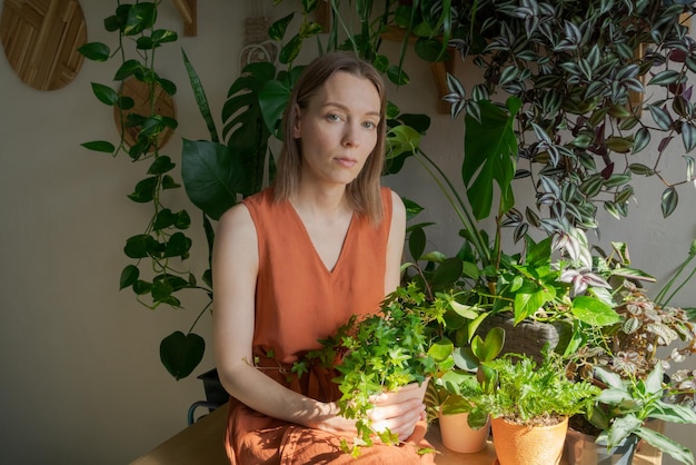 Mooie vrouw in oranje kleding zorgt voor Ficusbloesems tegen de achtergrond