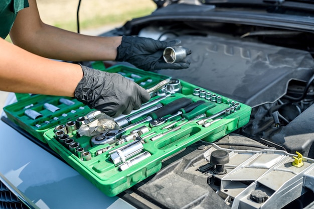 Mooie vrouw in overall met de sleutels die een kapotte auto tijdens haar reis herstellen