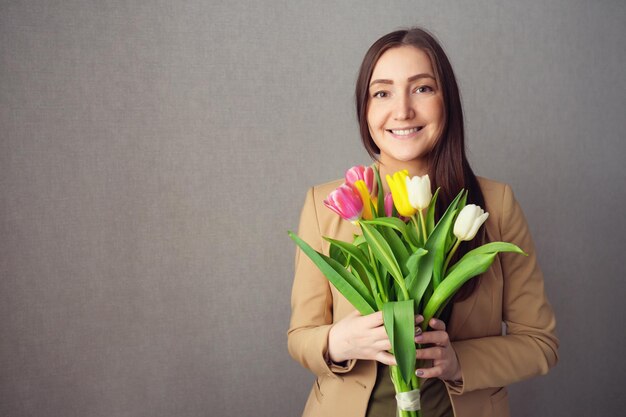 Mooie vrouw in pak met een boeket tulpen kopieer ruimte