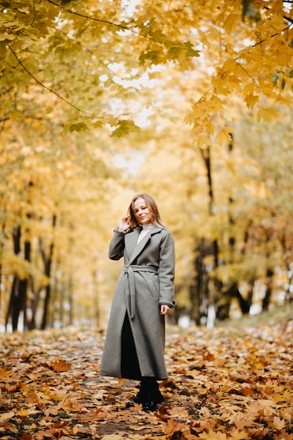 Mooie vrouw in park in herfst geel landschap van herfstbladeren