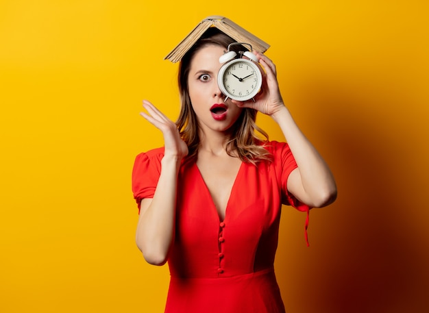 Mooie vrouw in rode jurk met wekker