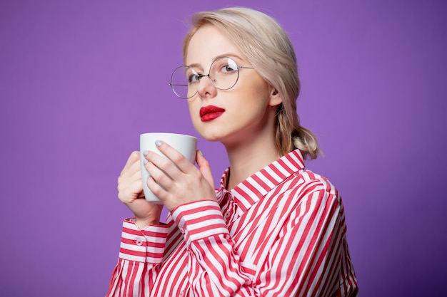 Mooie vrouw in rood gestreept overhemd met kop koffie