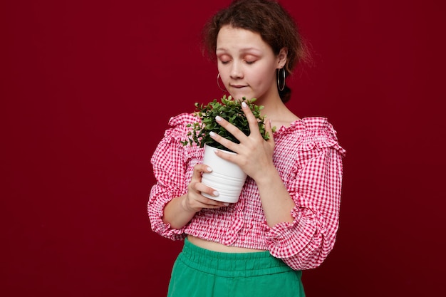 Mooie vrouw in roze blouse poseert met een plant in witte pot close-up