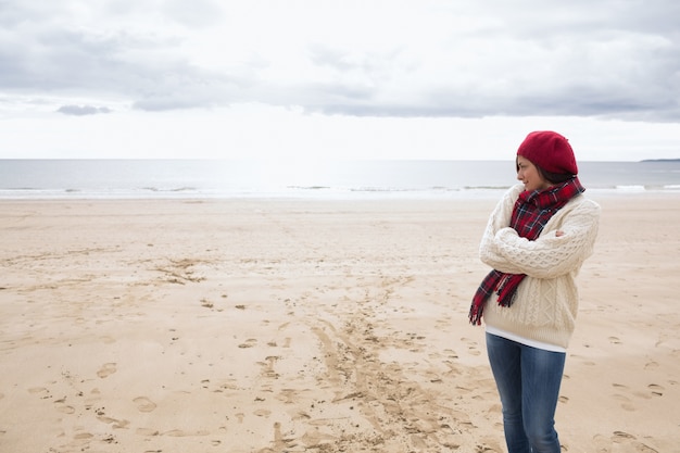 Mooie vrouw in stijlvolle warme kleding op het strand