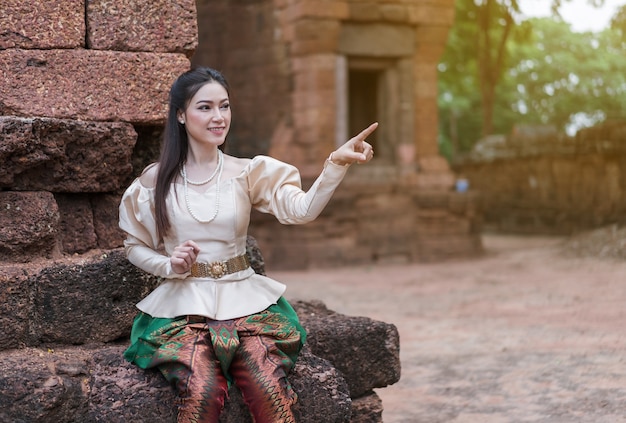 mooie vrouw in Thaise traditionele kleding wijst