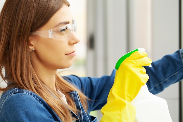 Mooie vrouw in uniform met benodigdheden die op kantoor schoonmaken.