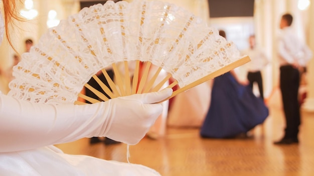 Mooie vrouw in vintage bal kostuum vrouw zwaaien met een ventilator close-up