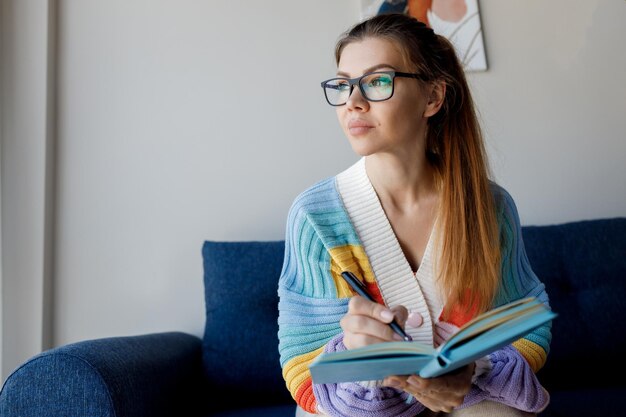 mooie vrouw in vrijetijdskleding studeert thuis met tablet en notebook