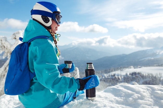 Mooie vrouw in winterkleren thee drinken in de bergen. Concept van reizen, vrije tijd, vrijheid, sport.