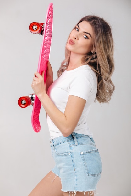 mooie vrouw in wit T-shirt met roze skateboard