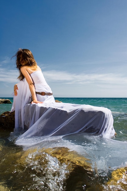 Mooie vrouw in witte jurk op het zeestrand