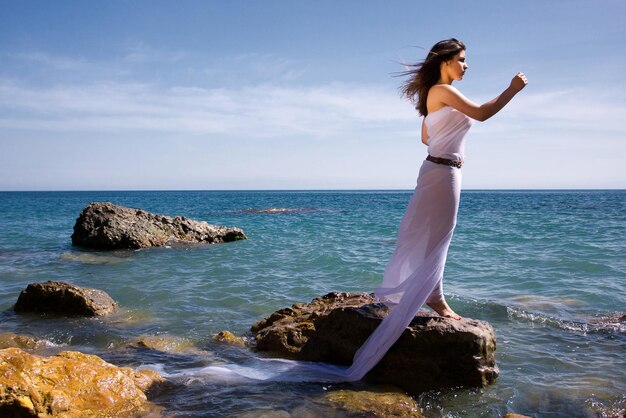 Mooie vrouw in witte jurk op het zeestrand