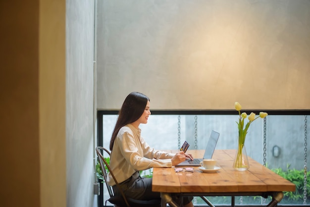 Mooie vrouw is online winkelen met creditcard in coffeeshop