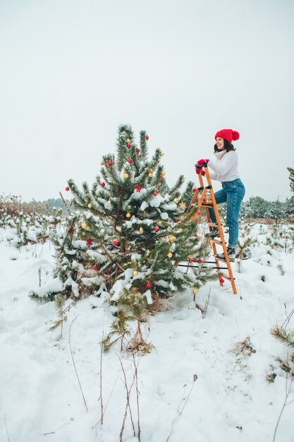 Mooie vrouw kerstboom buitenshuis versieren